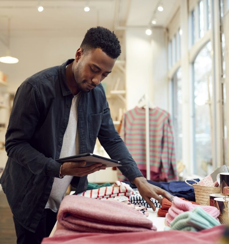 Male Small Business Owner Checks Stock In Shop Using Digital Tablet